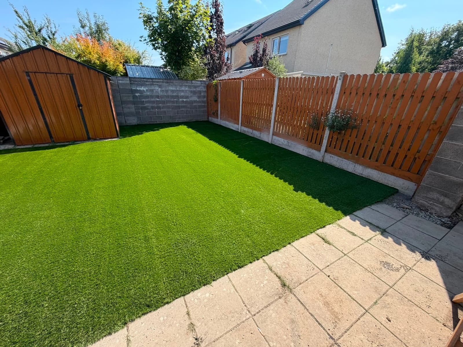 Artificial lawn between fence and shed
